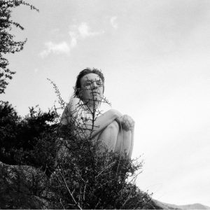 Tessa De Lyon sitting behind a bush